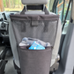 A black fabric vehicle laundry bag hanging from the head of a van seat, with a front pocket is waterproof