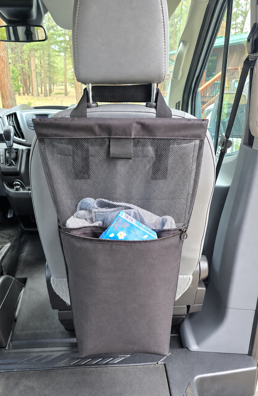 A black fabric vehicle laundry bag hanging from the head of a van seat, with a front pocket is waterproof