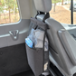 A black seat back bag hanging from the headrest of a gray vehicle seat, shown inside a van  used as a laundry bag.
